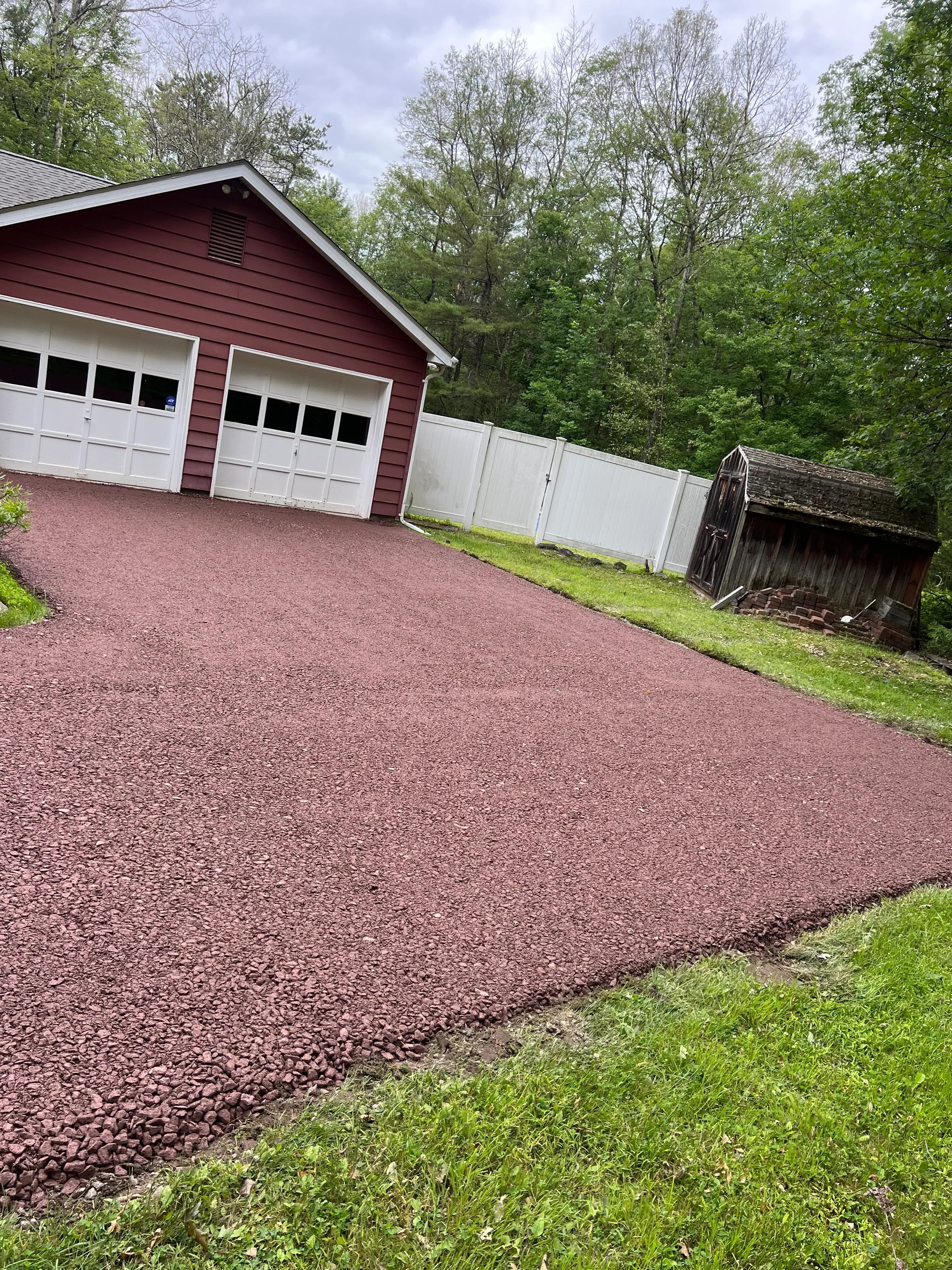 New asphalt driveway with burgundy-red surface and clean edges leading to residential home