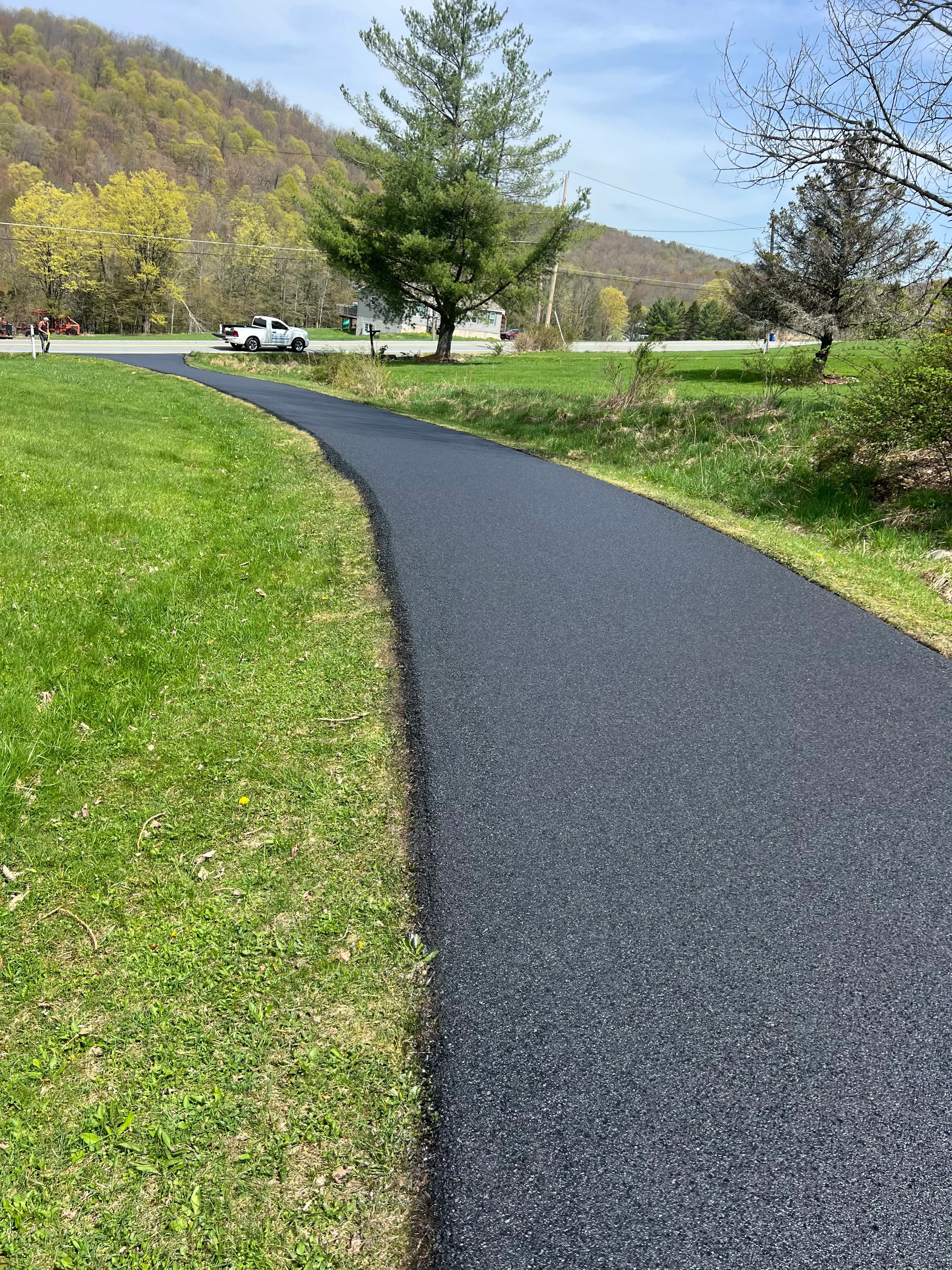 Newly installed black asphalt driveway with clean edges and proper grading