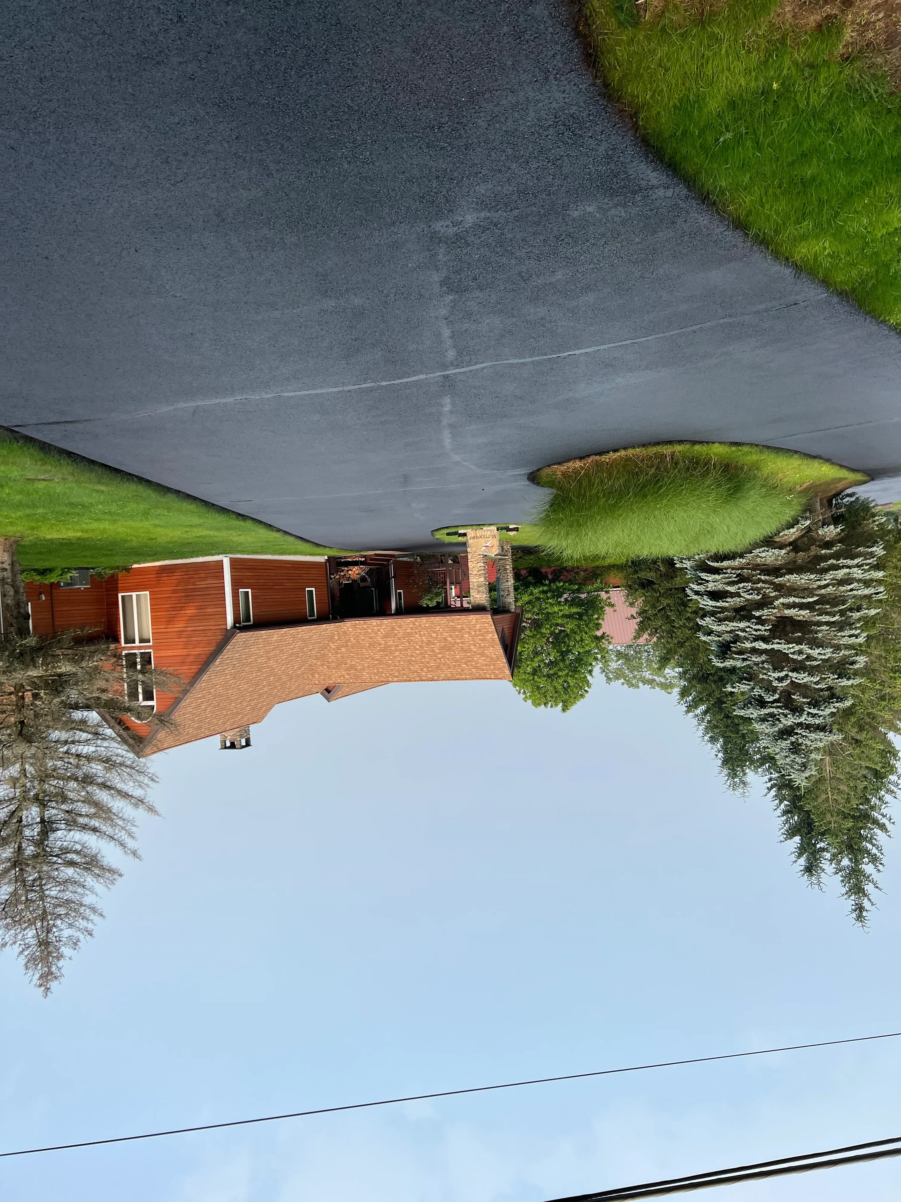 New asphalt driveway alongside brick home with green lawn and landscaping