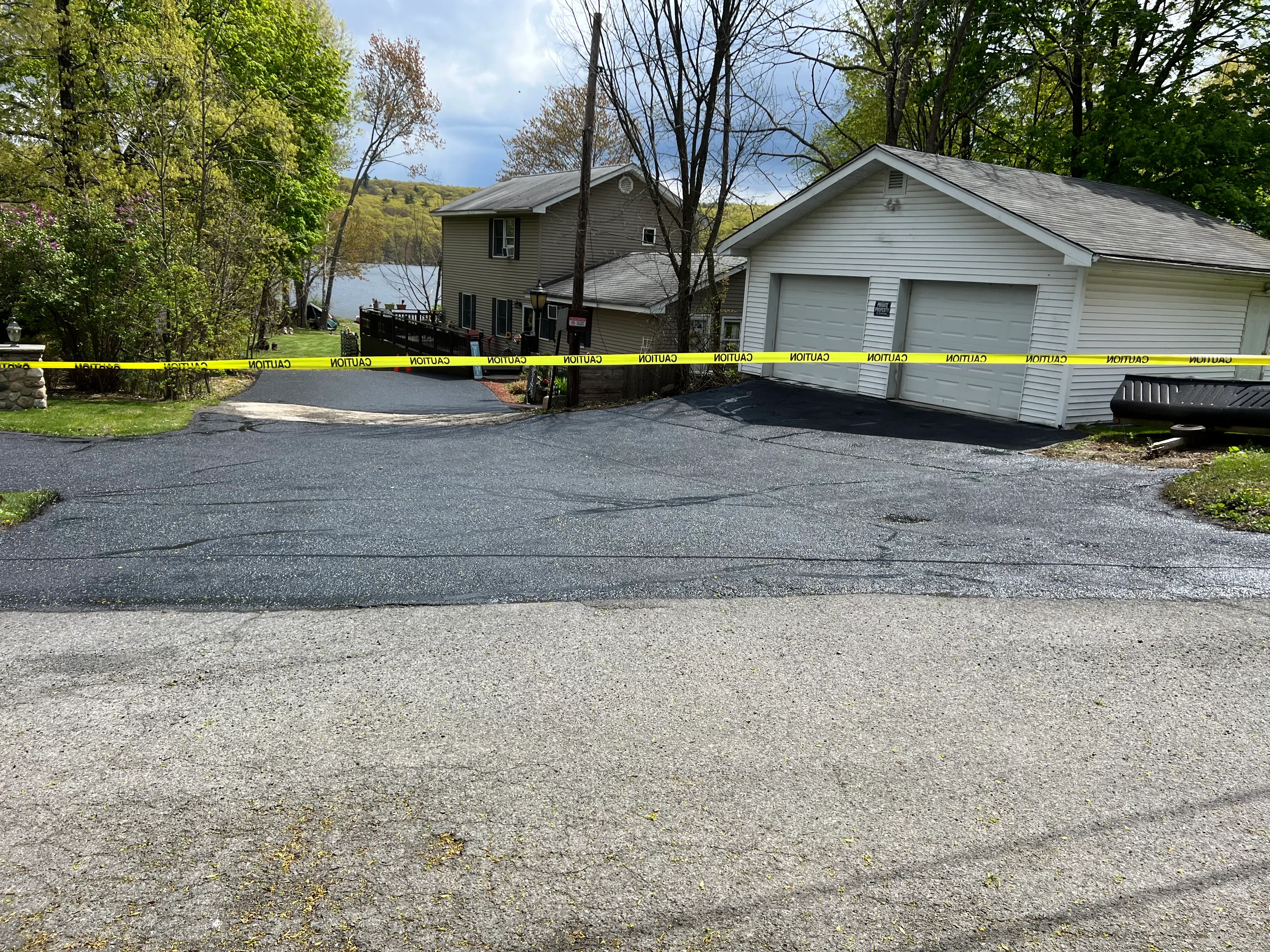 Newly paved asphalt driveway with smooth black surface in front of two-car garage and residential home
