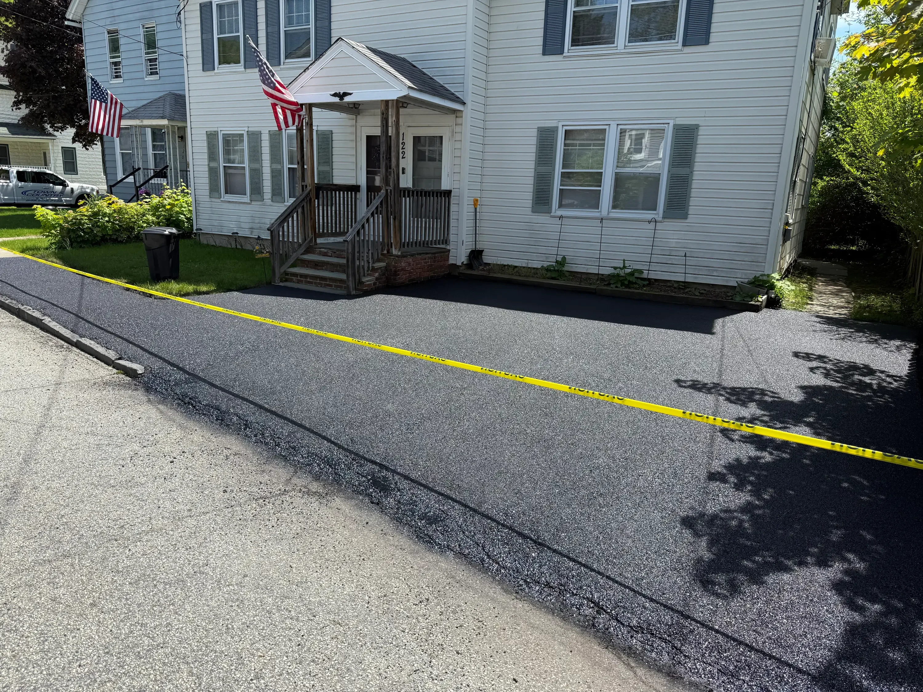 Newly paved residential asphalt driveway with dark gray surface and defined edge lines