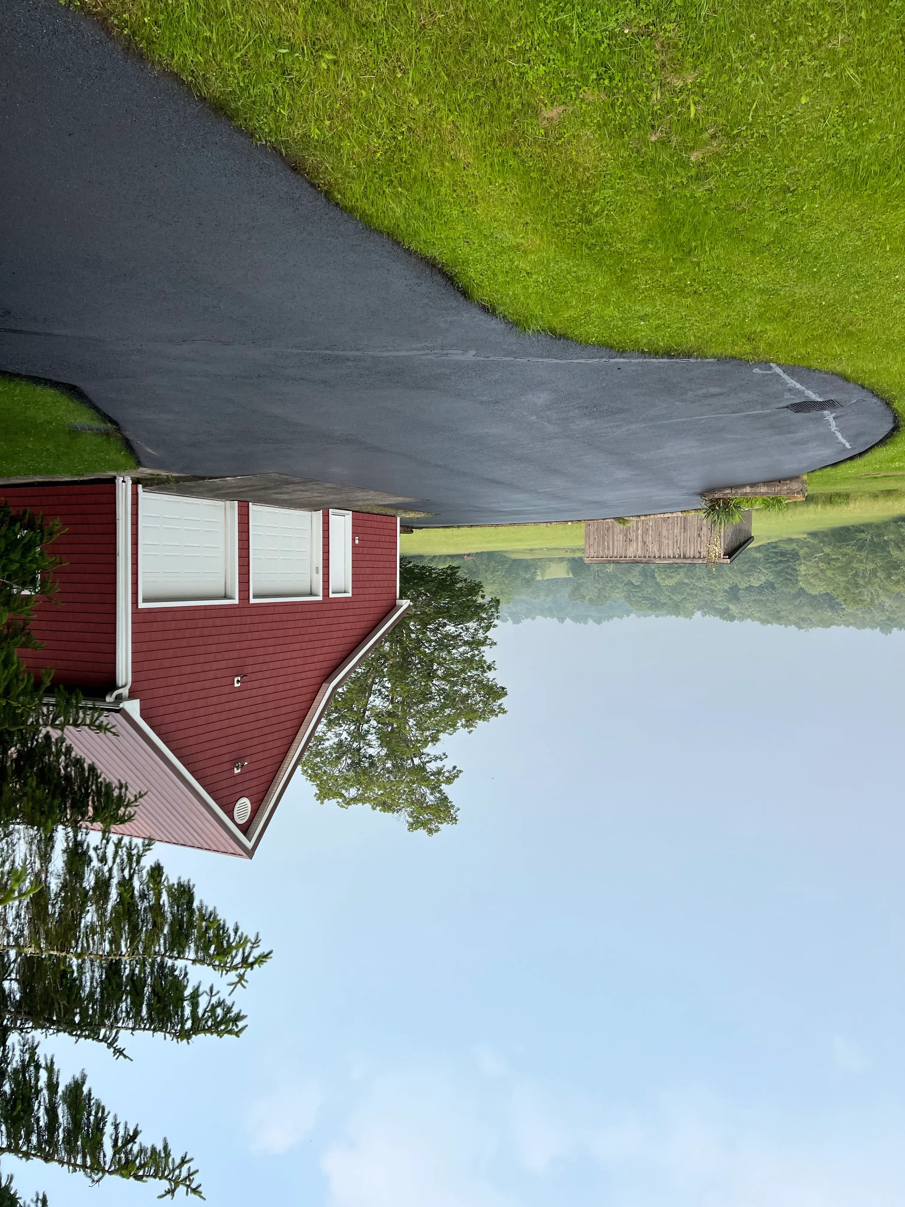 New asphalt driveway with smooth dark surface adjacent to residential home with red metal roof