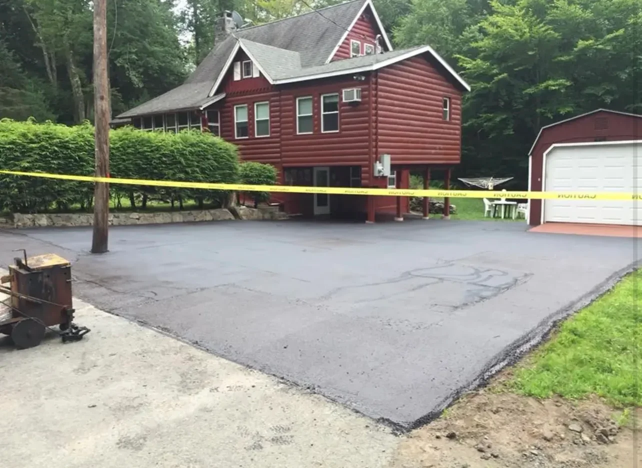 Newly installed asphalt driveway with compacted surface and defined edges at residential home