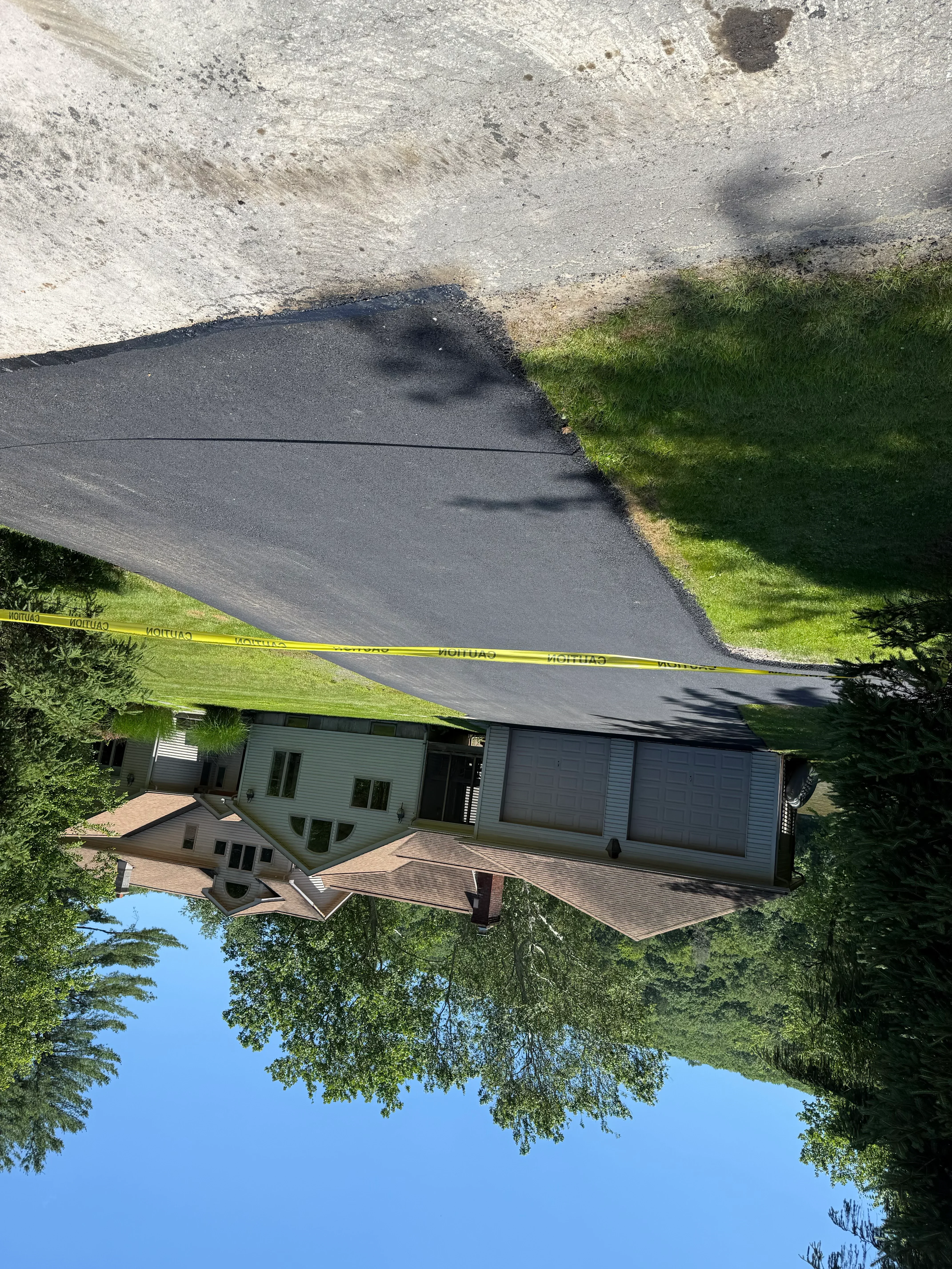 Newly installed dark asphalt driveway with clean edges and proper drainage slope