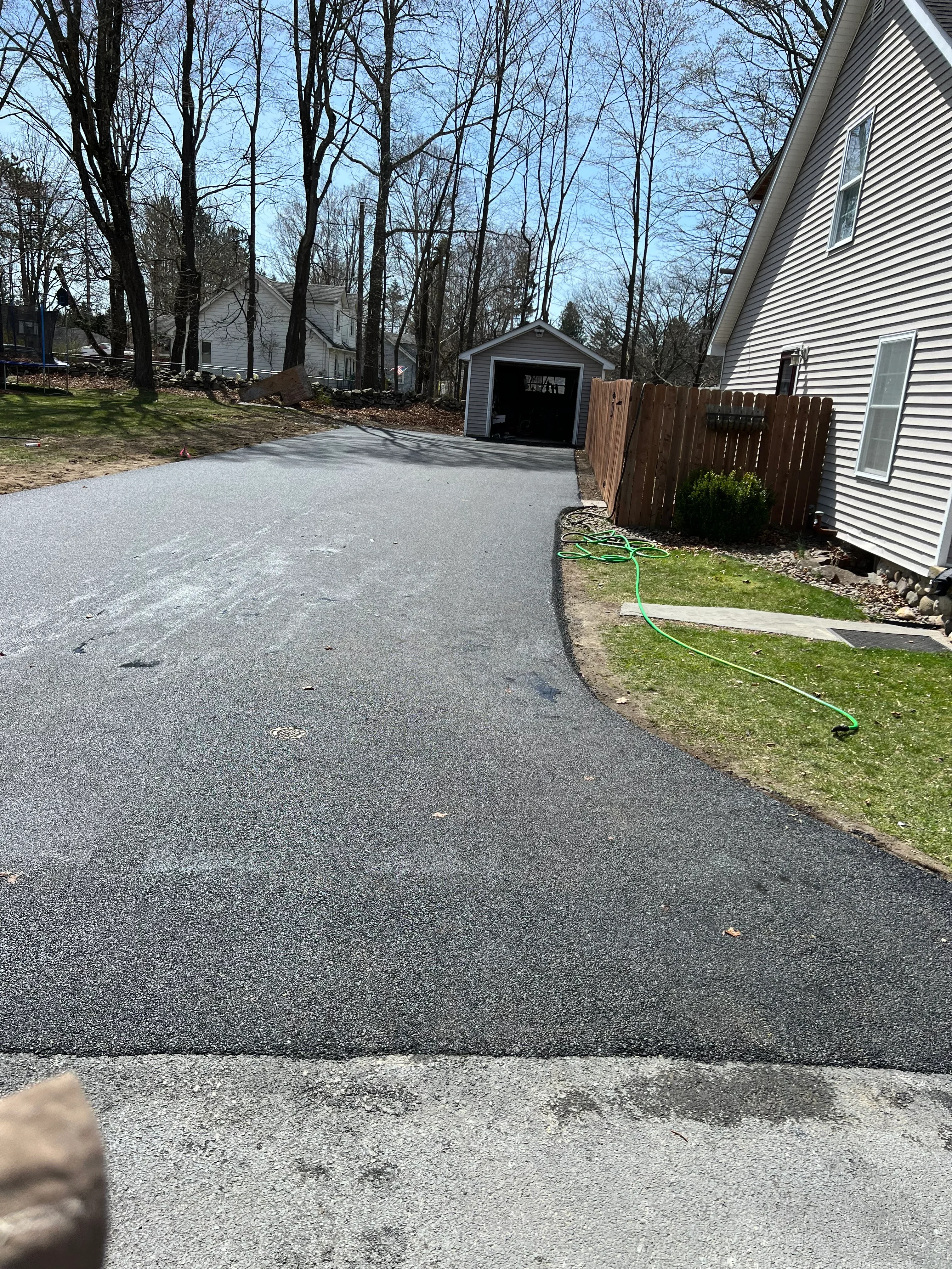 New asphalt driveway with metal building and lawn edging