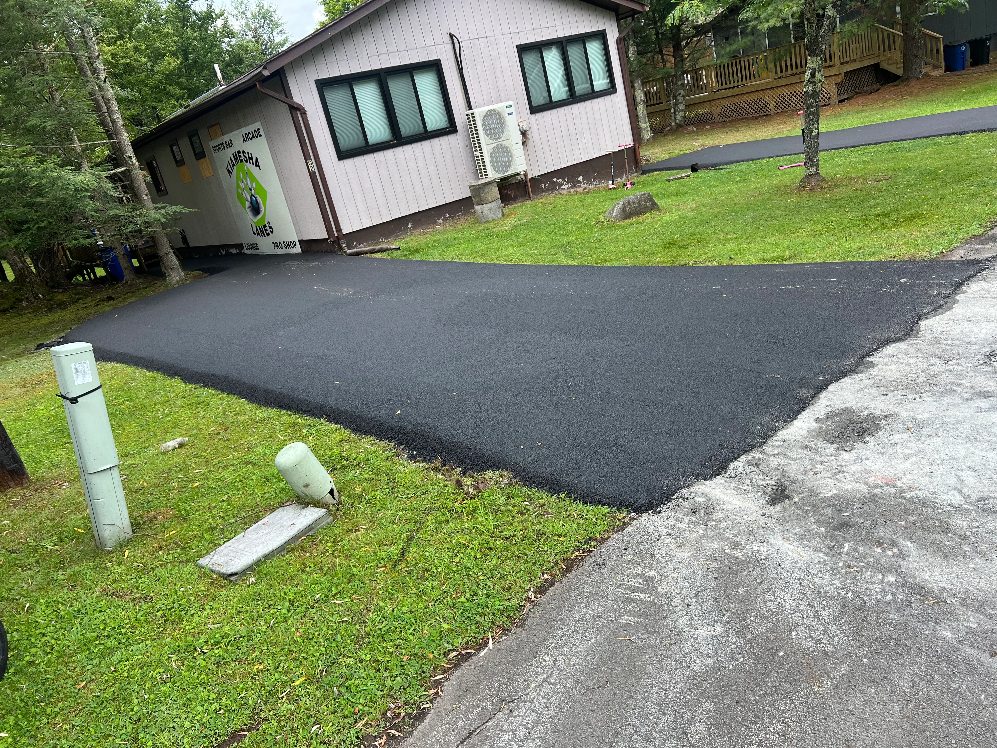 New black asphalt driveway with smooth finish in front of residential home